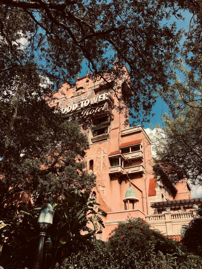 Spooky Hollywood Tower Hotel nestled among trees under a clear blue sky, evoking a mysterious atmosphere.