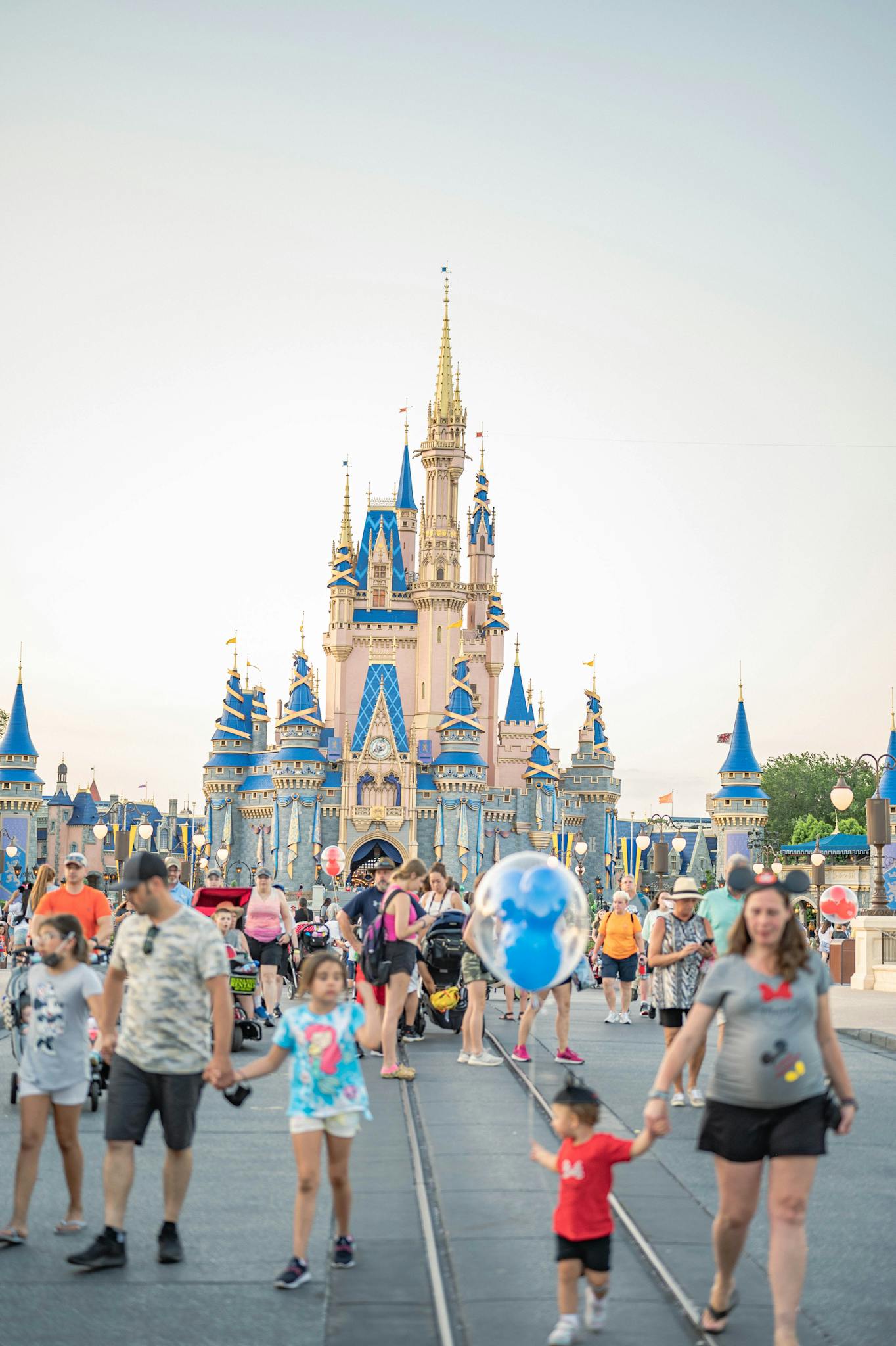 Tourists and families exploring a famous theme park with a castle landmark.